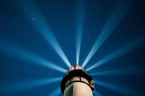 stars light up the sky behind lighthouse