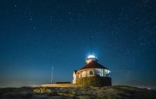 clear night shows a lot of stars over the lighthouse
