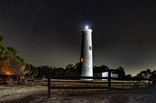 night view of the lighthouse from behind an old wood fence