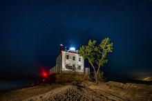 stars fill the night sky behind the lighthouse